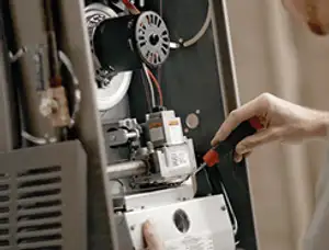 Furnace repair technician inspecting internal components and wiring in Dayton, OH