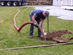 Septic pumping technician servicing a residential septic tank with a vacuum hose in Dayton, OH