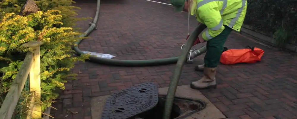 Septic tank cleaning technician servicing a septic tank with a vacuum hose in Dayton, OH