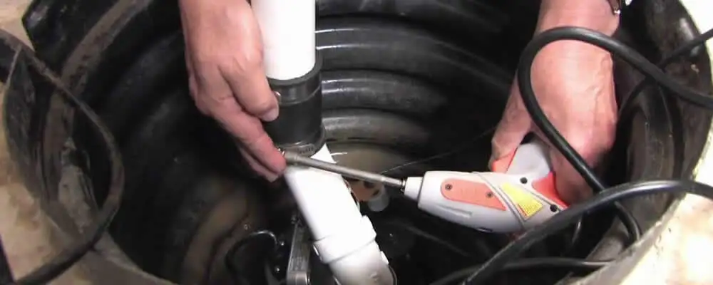 Sump pump installation technician connecting PVC discharge piping in Dayton, OH