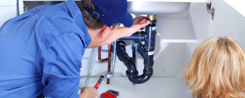 Plumber repairing under-sink drain pipes and fittings in Dayton, OH